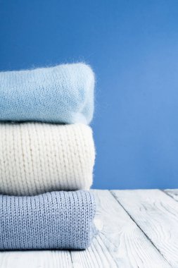 Örme yün kazaklar. Örme kış yığını, mavi sonbahar giysileri, ahşap arka plan, kazak, triko, metin için alan.