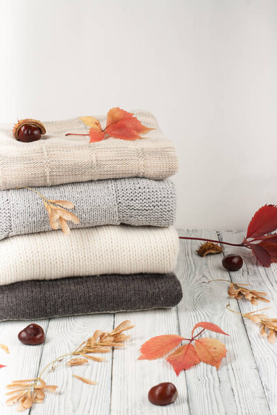 Knitted wool sweaters. Pile of knitted winter, autumn clothes on wooden background, sweaters, knitwear, space for text.