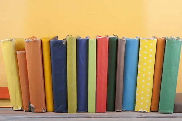 Book stacking. Open hardback books on wooden table and yellow background. Back to school. Copy space for ad text