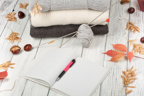 Camisolas de lã de malha. Pilha de inverno de malha, roupas de outono em fundo de madeira, blusas, malhas, caneta, livro, espaço para texto . — Fotografia de Stock