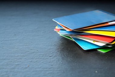 Siyah arka plan üzerinde banka kartları yığını.