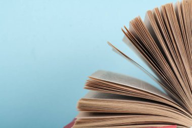 Kitap istifleme. Açık kitap, ahşap masa ve mavi arka plan üzerine ciltli kitaplar. Okula dönelim. Metin için alanı kopyala.