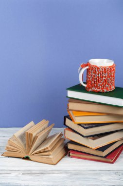 Kitap istifleme. Açık kitap, ahşap masa ve mavi arka plan üzerine ciltli kitaplar. Okula dönelim. Metin için alanı kopyala.