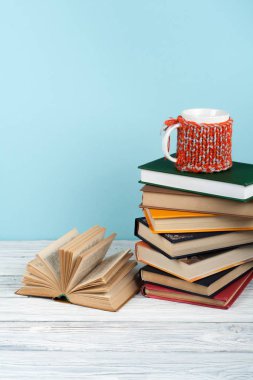 Kitap istifleme. Açık kitap, ahşap masa ve mavi arka plan üzerine ciltli kitaplar. Okula dönelim. Metin için alanı kopyala.