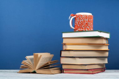 Kitap istifleme. Açık kitap, ahşap masa ve blu üzerinde ciltli kitaplar.