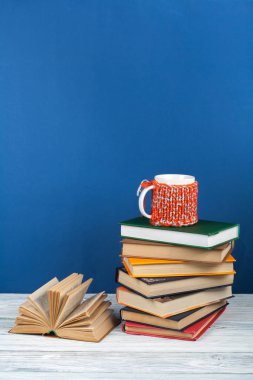 Kitap istifleme. Açık kitap, ahşap masa ve mavi arka plan üzerine ciltli kitaplar. Okula dönelim. Metin için alanı kopyala.