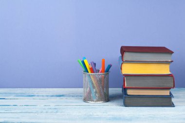 Kitap istifleme. Açık kitap, ahşap masa ve blu üzerinde ciltli kitaplar.