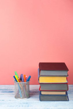 Kitap istifleme. Açık bir kitap, ahşap masa ve kırmızı arka plan üzerine ciltli kitaplar. Okula dönelim. Metin için alanı kopyala.