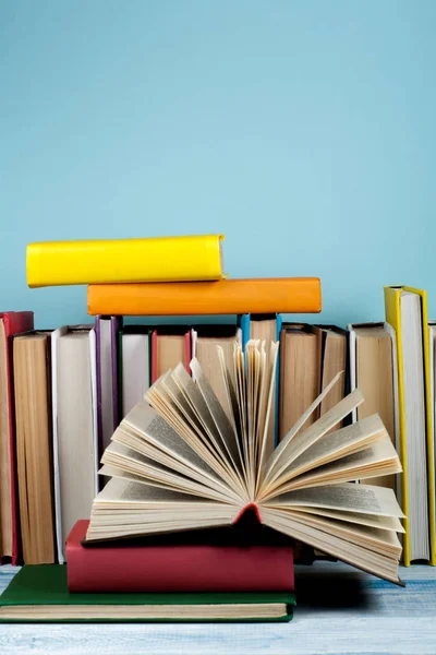 书堆放。打开的书，木制桌子上的精装书和蓝色背景的书。回学校去文本的复制空间. — 图库照片