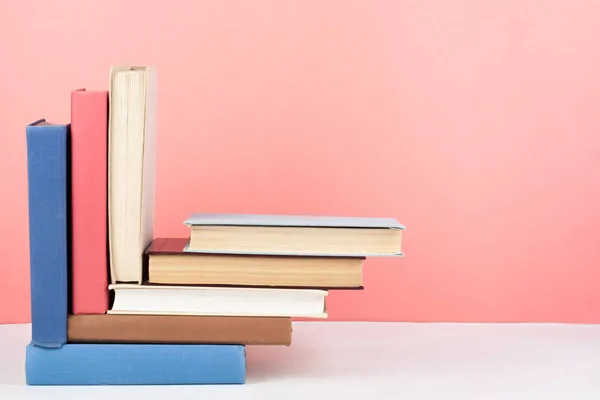 Nyílt könyv, keménykötésű színes könyvek fából készült asztal, piros, rózsaszín háttér. Vissza az iskolába. Hely másolása a szöveghez. Oktatásügyi üzleti koncepció. — Stock Fotó