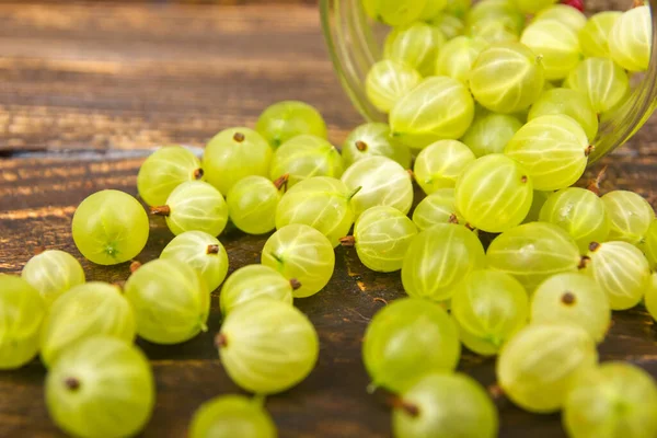 Stachelbeeren auf hölzernem Tischhintergrund, verschüttet aus einem Gewürzglas. .Antioxidantien, Detox-Diät, Bio-Früchte. Beeren — Stockfoto