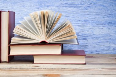 Açık bir kitap, mavi arka planda kitaplar. Okula dönelim. Eğitim. Metin için alanı kopyala