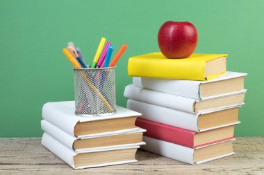 Kitaplar istifleniyor. Tahta masadaki kitaplar ve yeşil arka plan. Okula dönelim. Reklam metni için alanı kopyala