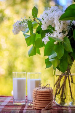 Birkaç kurabiye, bardak süt ve çiçekler