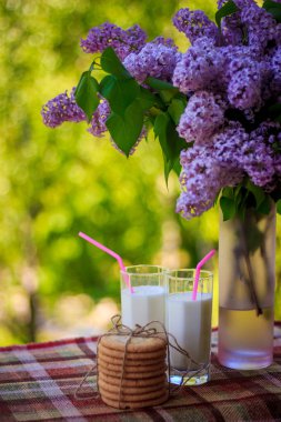 Birkaç kurabiye, bardak süt ve çiçekler