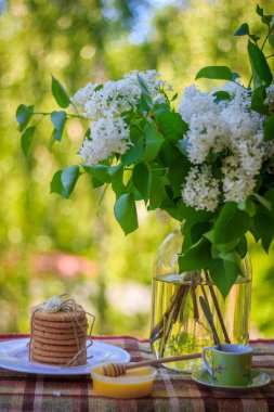 Bardak çay bisküvi ile bir Vazoda Çiçekler