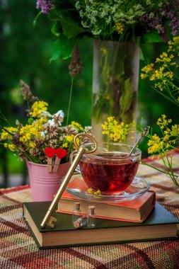 Bir fincan çay ve kır çiçekleri pembe demir kova