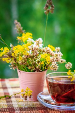 Bir fincan çay ve kır çiçekleri pembe demir kova