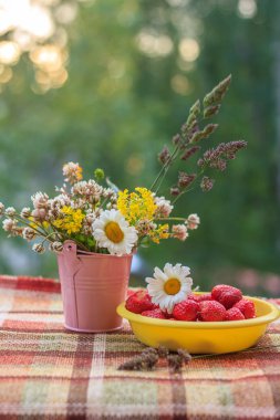 Bir tabak çilek ve kır çiçekleri