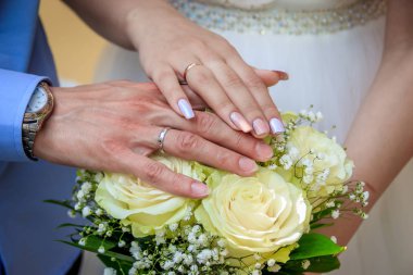 Gelin ve damat buket halkaları ile elleri. Düğün süslemeleri. Düğün süslemeleri. Alyans.
