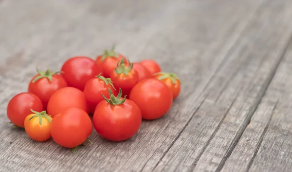 Cherry tomatoes on a wooden background. Autumn harvesting. — Stock Image Cherry tomatoes on a wooden background. Autumn harvesting. Stock Image
