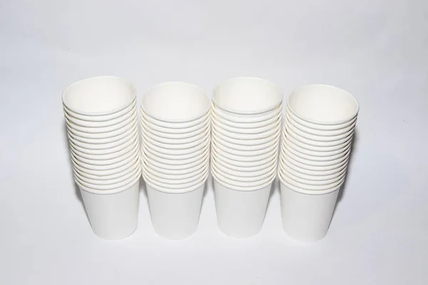 White paper cups for tea on a white background. Isolated objects. Beverages. Gently hot. Disposable tableware. Dishes for a picnic.