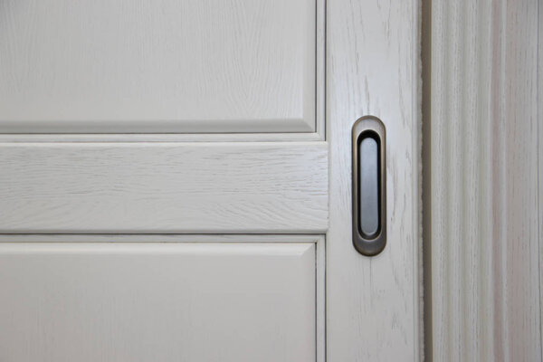 Тёмная ручка на белом фасаде шкафа. Мебельная фурнитура. Откройте и закройте шкаф
.