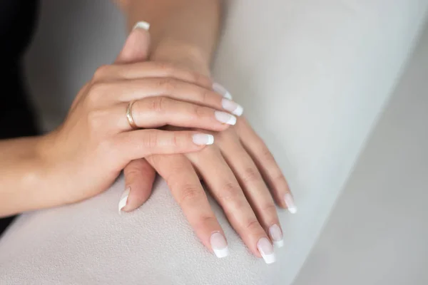 White manicure on the hands of a woman. Female manicure. Fake nails are glued.