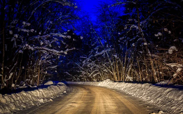 Snowy evening road. Winter tale on the road. Travel by car in winter