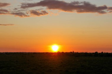 Şehir dışında manzara. Çimenli alan ve mavi gökyüzü. Sunset village alanın üzerinde. Günbatımı alanında şehir dışında