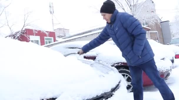 Un uomo pulisce la macchina dalla neve. L'auto era coperta di neve. Russia, Gatchina, 26 dicembre 2018 — Video Stock