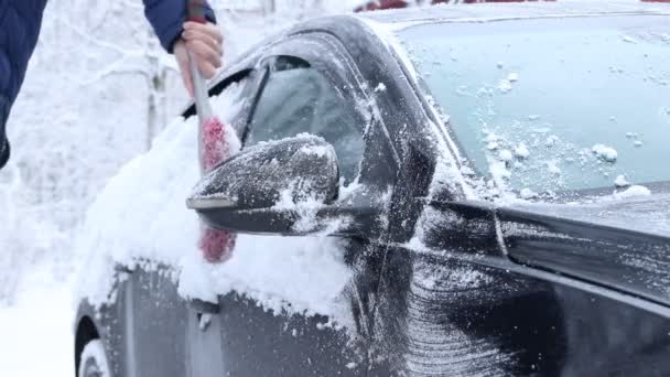 A man cleans the car from the snow. The car was covered with snow. — Stock Video