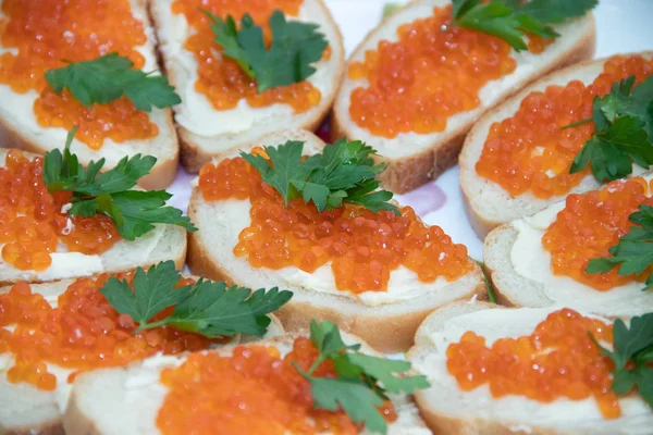 Sanduíches com caviar. Caviar vermelho. Comida na mesa de férias. Lanches em uma chapa . — Fotografia de Stock