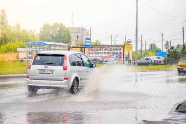 Arabadan yola su sıçratıyor. Yaz yağmuru. Yolda su birikintileri var. Rus yolları. Isliyiz sokağı. Su sıçratıyor. Rusya, Leningrad bölgesi Gatchina 21 Temmuz 2018