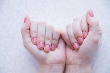 Kadın ellerde pembe masif renk manikür. Nazik manikür. Jel cila. Bakımlı tırnaklar. Monofonik manikür