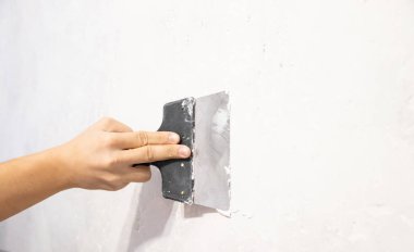 Duvara macun uygulayan bir spatula ile erkek el. Apartman onarımı