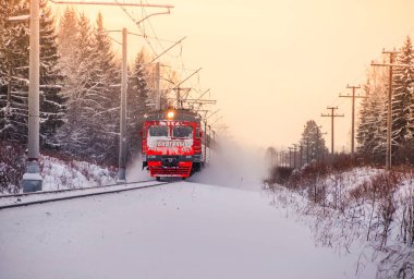 Kış ormanı boyunca raylar üzerinde Kırmızı Rus treni, Rusya, Leningrad bölgesi, Gatchina bölgesi, Ocak 6, 2019
