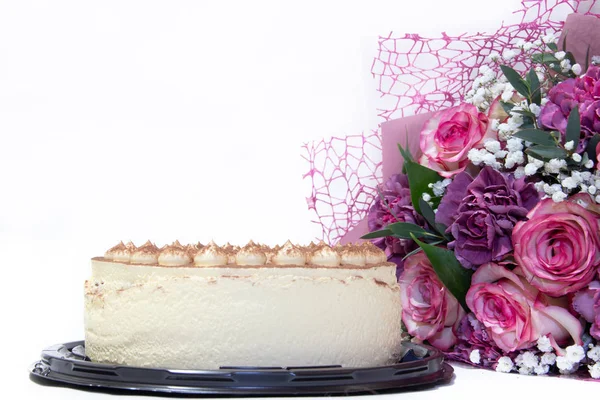 delicious tiramisu cake and bouquet of pink flowers isolated on white background