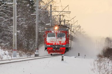 Kış ormanı boyunca raylar üzerinde Kırmızı Rus treni, Rusya, Leningrad bölgesi, Gatchina bölgesi, Ocak 6, 2019