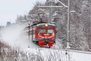Kış ormanı boyunca raylar üzerinde Kırmızı Rus treni, Rusya, Leningrad bölgesi, Gatchina bölgesi, Ocak 6, 2019