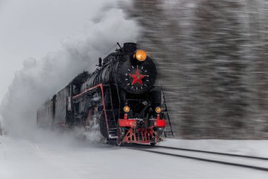 Kış ormanı boyunca raylar üzerinde eski buharlı lokomotif, Rusya, Leningrad bölgesi, Gatchina bölgesi, 6 Ocak 2019