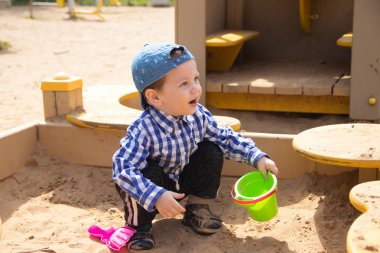 Küçük çocuk kum havuzunda oyuncaklar ve kum ile oynuyor