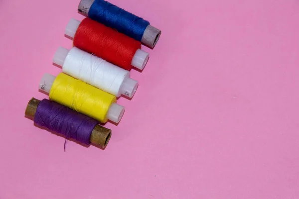 set of colored threads on pink background