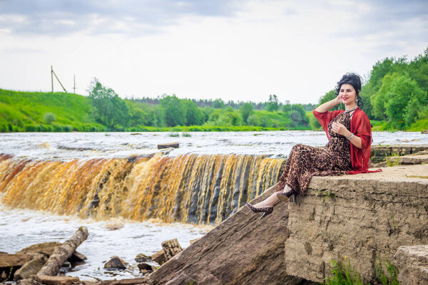 Woman on the waterfalls. Little waterfall. Camping. . Young woman. Woman in a dress.
