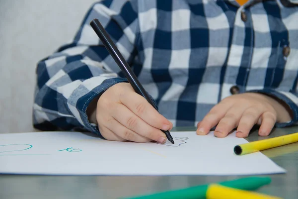 Little boy drawing with felt-tip pens on paper. Developmental activities.