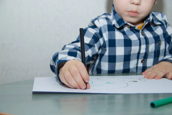 Little boy drawing with felt-tip pens on paper. Developmental activities.