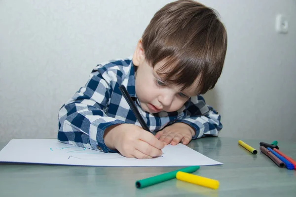 Little boy drawing with felt-tip pens on paper. Developmental activities.