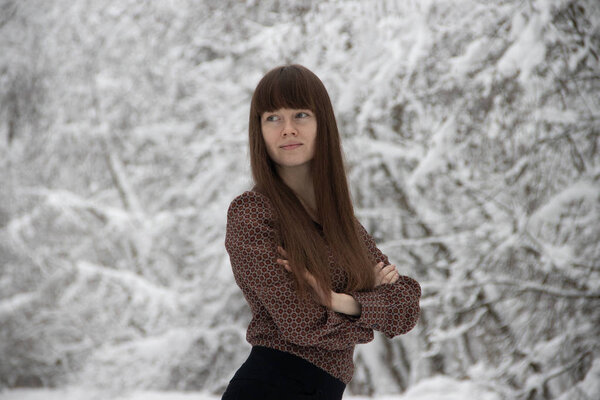 young woman posing in winter forest with snowy trees