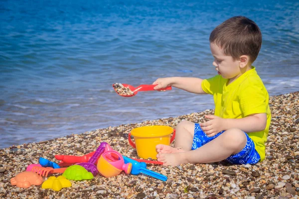 Piccolo Ragazzo Che Gioca Sulla Spiaggia Ghiaia Con Giocattoli Colorati — Foto Stock