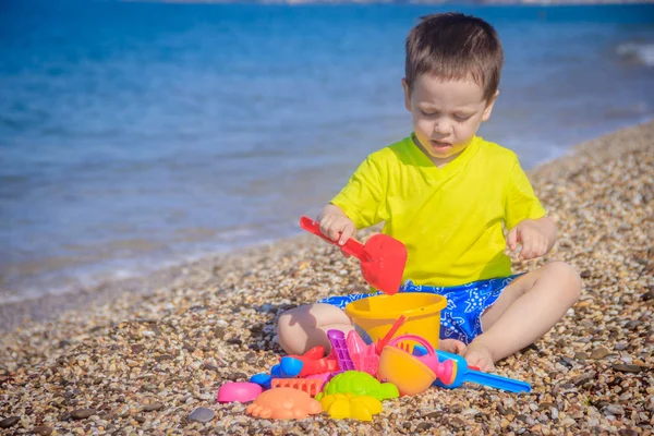 Piccolo Ragazzo Che Gioca Sulla Spiaggia Ghiaia Con Giocattoli Colorati — Foto Stock